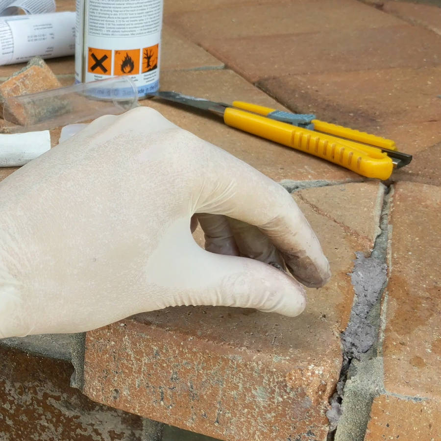 Using concrete repair stick putty to bond bricks and pavers back together